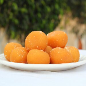 A plate of delicious orange laddu sweets outdoors, exuding traditional South Asian flavors.