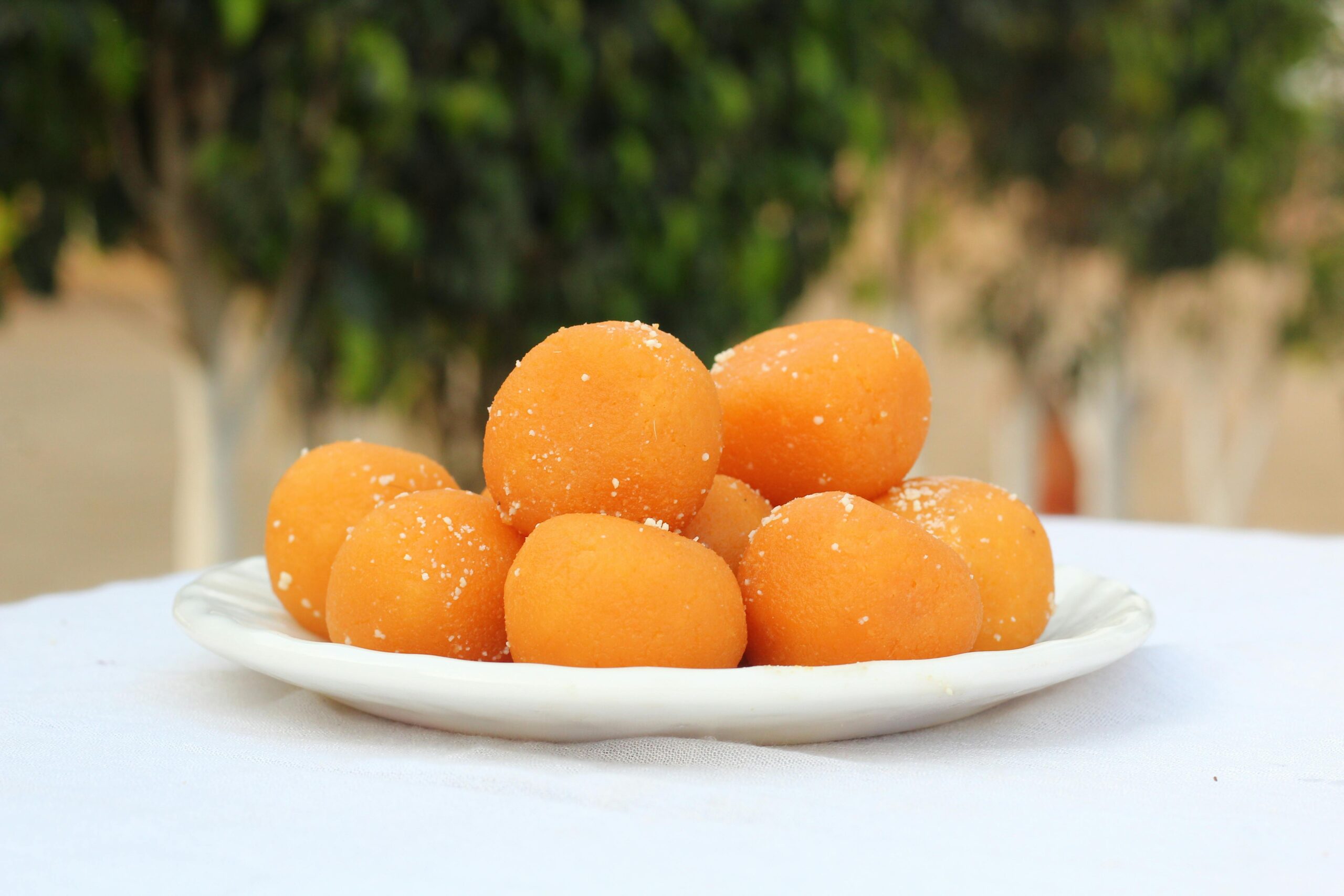 A plate of delicious orange laddu sweets outdoors, exuding traditional South Asian flavors.
